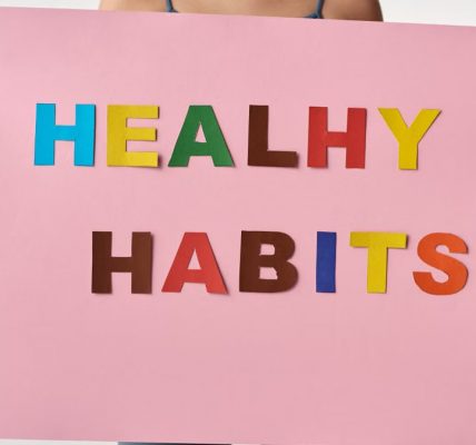 A woman holds a pink poster with colorful letters spelling 'HEALTHY HABITS'.