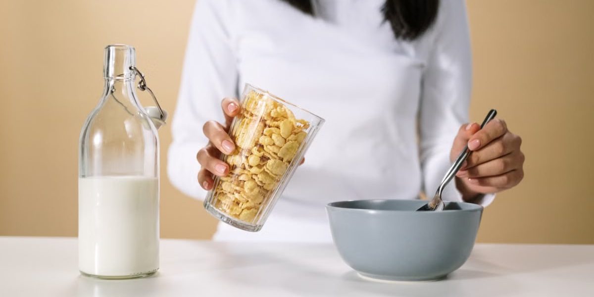 Person pouring cereal into a bowl with a bottle of milk nearby, ready for breakfast.